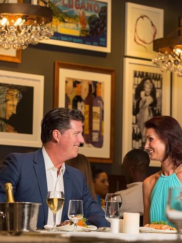 Couple dining by framed art under crystal chandeliers in Abbiocco at Warwick Paradise Island Bahamas