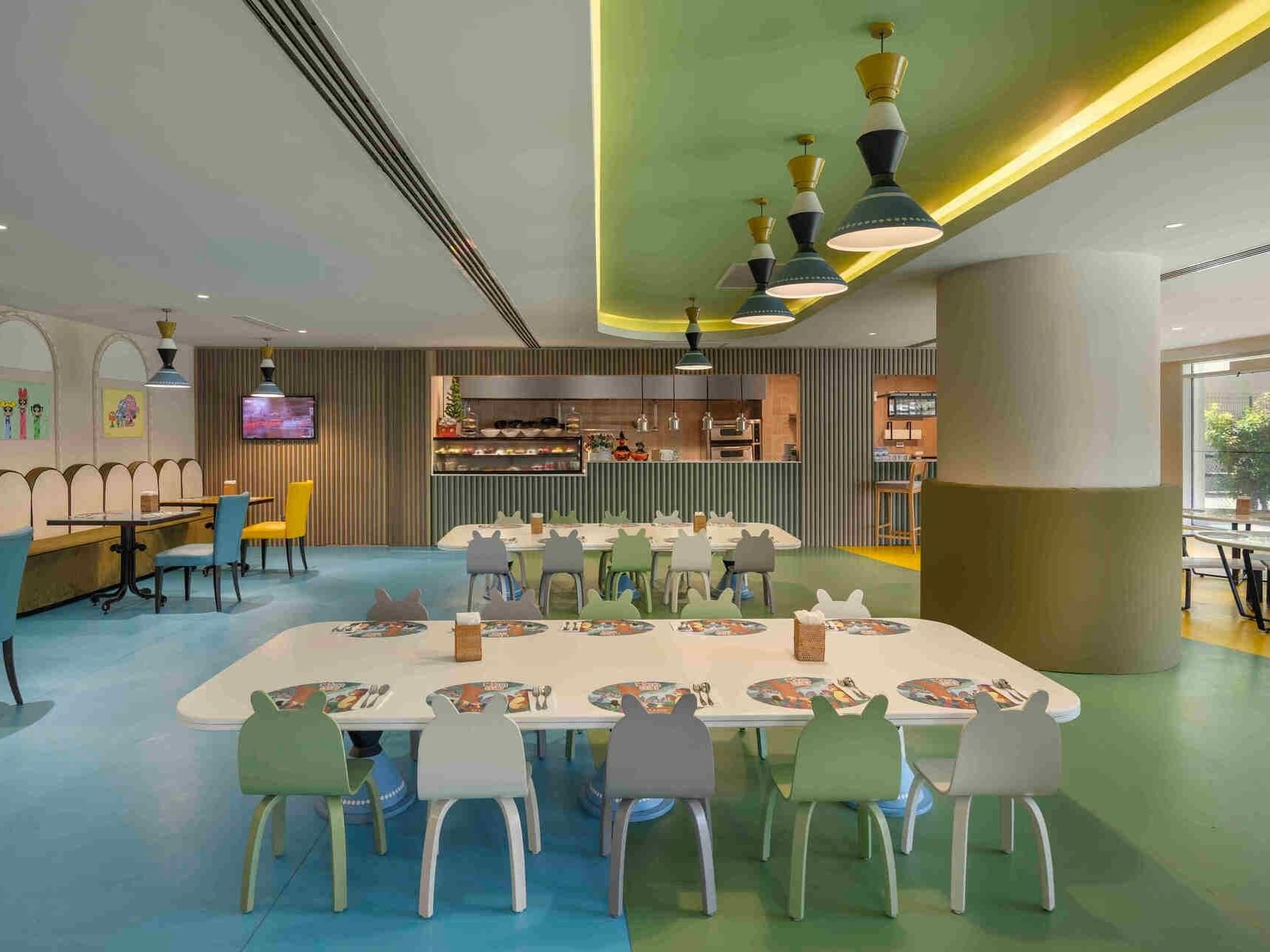 Colorful children's dining area with playful decor, white tables, and mint green chairs at Titanic Deluxe Golf Belek.
