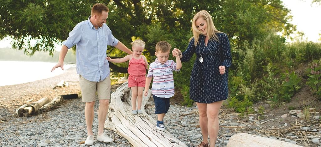 family walking along driftwood on a rocky shoreline