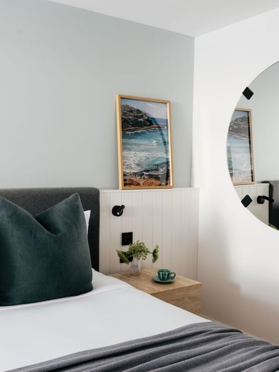 Wellness Suite Twin at Elysium Manly with teal velvet cushions by a wooden nightstand under framed ocean art