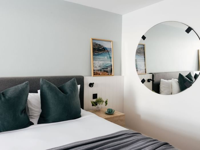 Atrium King at Elysium Manly with teal velvet cushions by a nightstand near a round mirror, offering cozy Manly accommodation