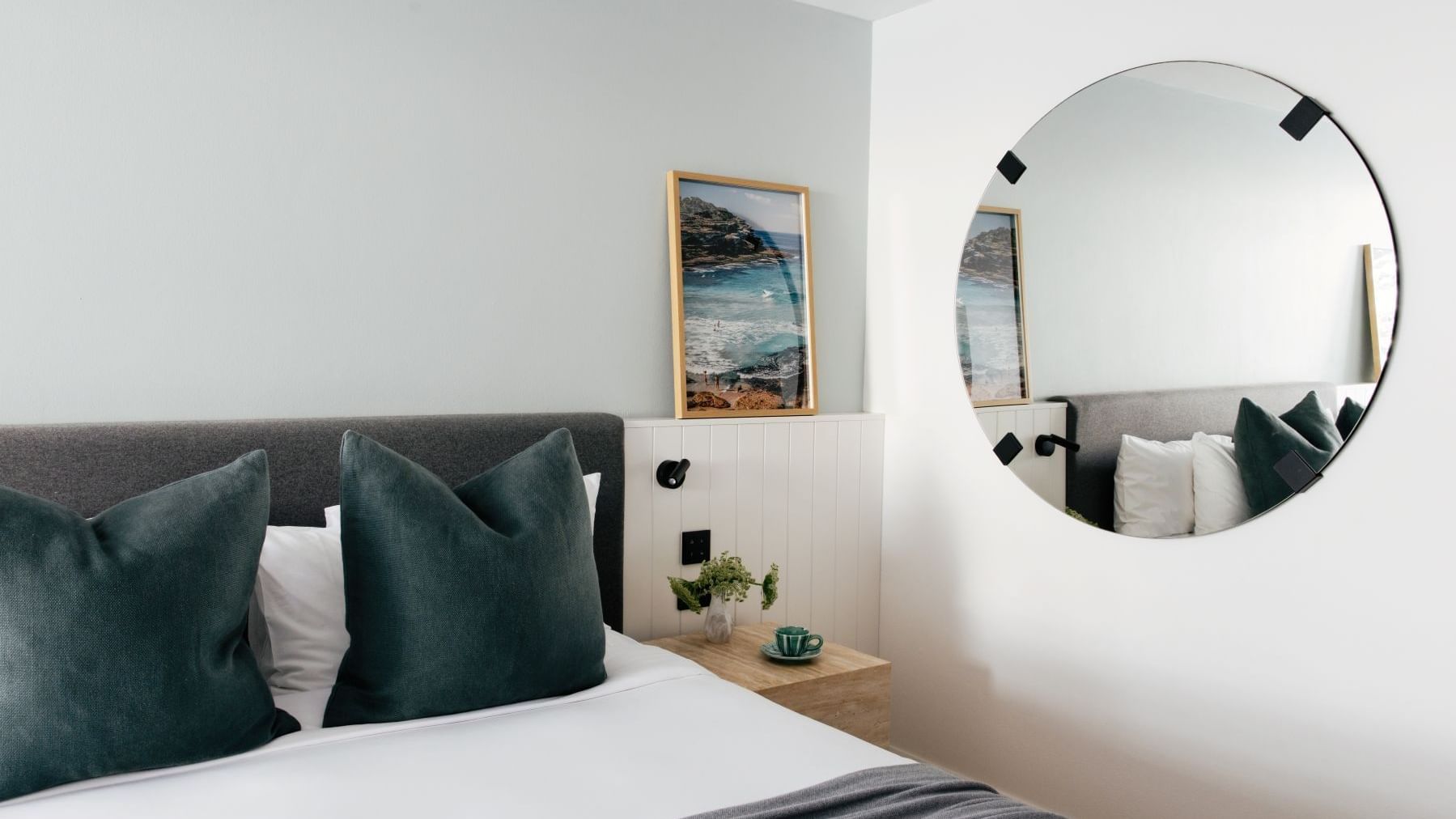 Atrium King at Elysium Manly with teal velvet cushions by a nightstand near a round mirror, offering cozy Manly accommodation