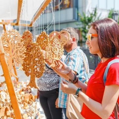 A woman tourist at a souvenir fair choosing handmade decorative wood carvings.