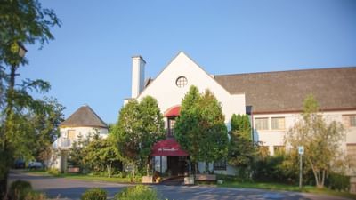 Exterior view of the La Tourelle Hotel and Spa framed by green trees under a clear blue sky