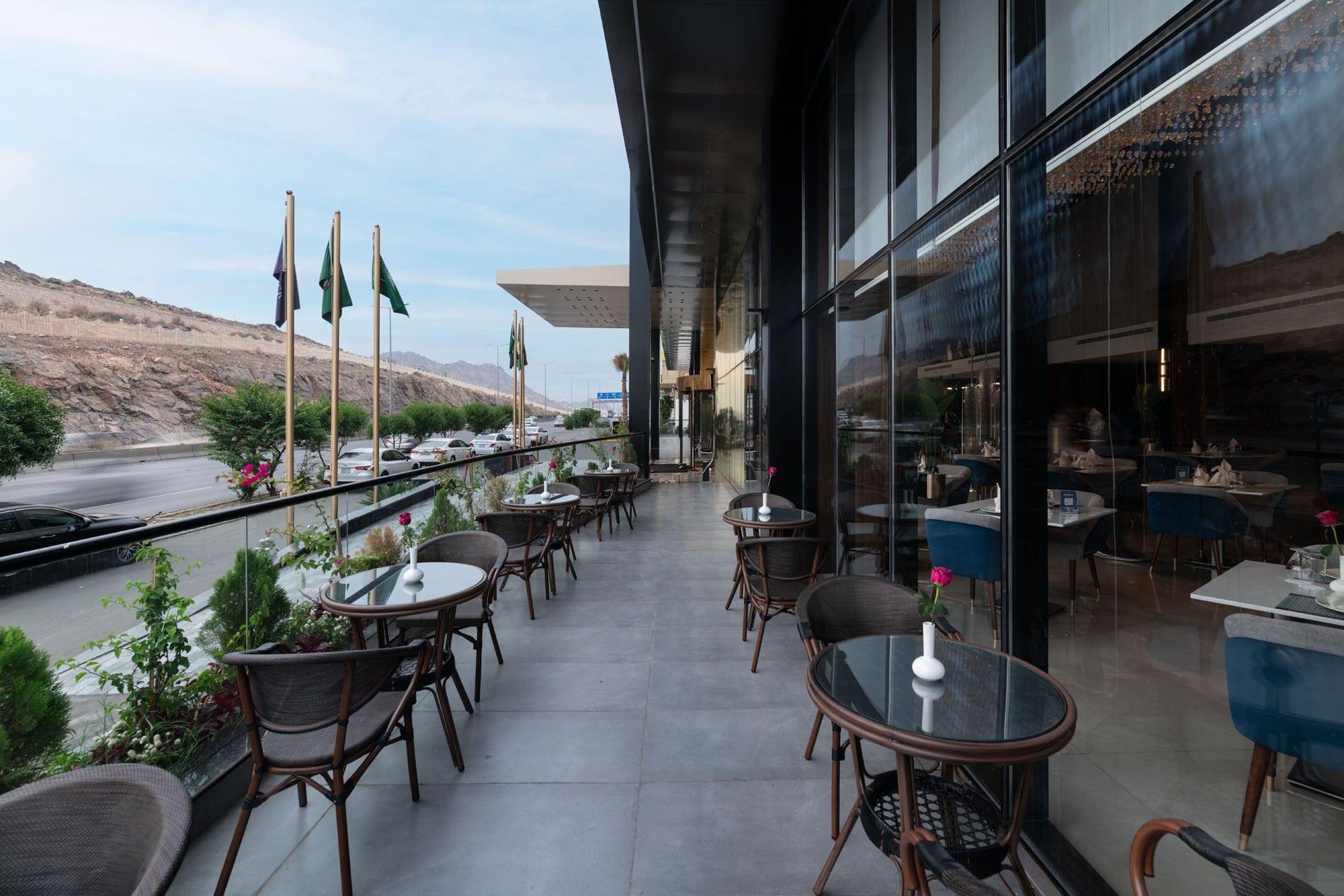Khva Cafe tables by a glass railing under a black awning on the outdoor terrace at Warwick Al Taif Hotel