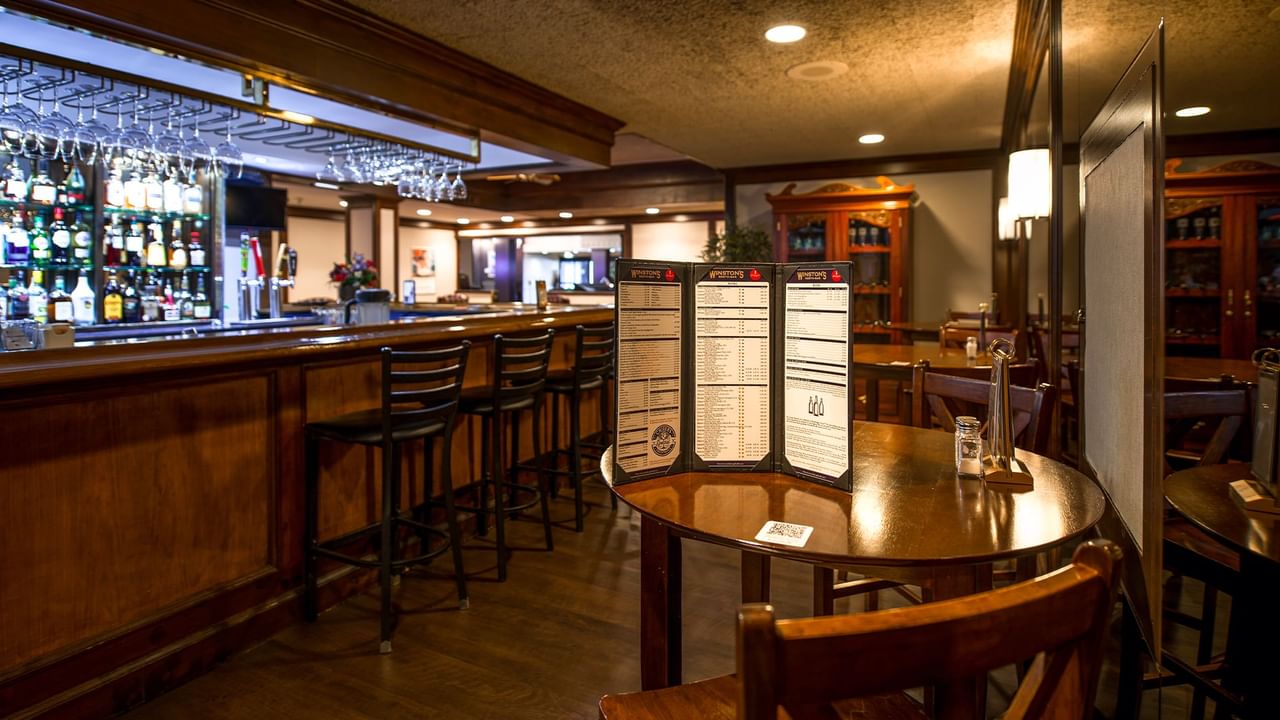 Interior of Winston's Resto-Bar with wooden furniture, a menu on a table, and shelves stocked with bottles.
