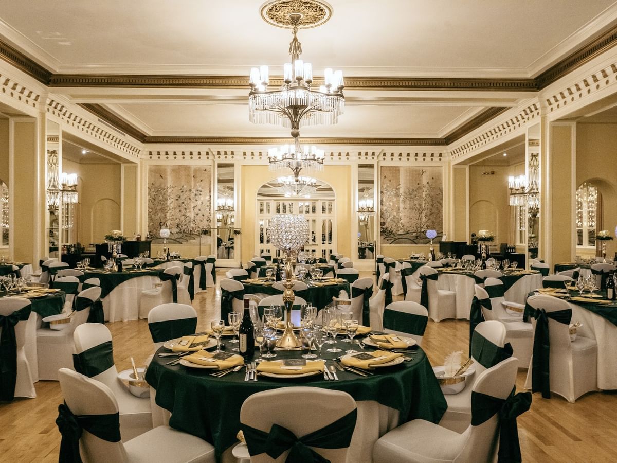Crystal ballroom with green tablecloths, white chair bows and large chandeliers at Arlington Resort Hotel & Spa