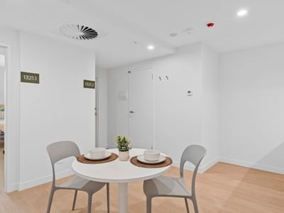 Dining area with a table, chairs, and a view of a bedroom at UniLodge Brisbane City.