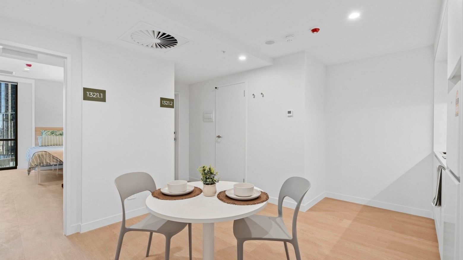 Dining area with a table, chairs, and a view of a bedroom at UniLodge Brisbane City.
