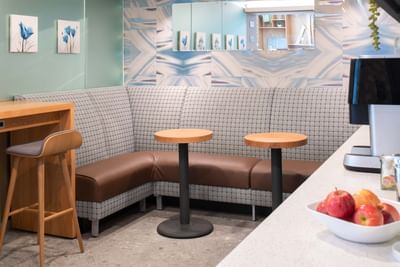 Cozy banquette seating, featuring a brown leather cushion under two round wooden tables at Hotel Keen
