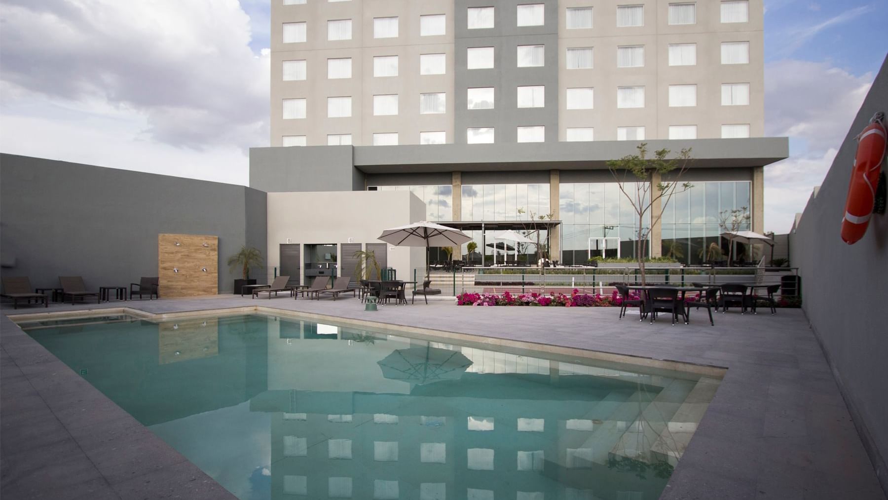 Exterior view of Fiesta Inn Suites Aeropuerto del Bajío outdoor pool area with lounge chairs