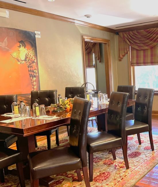 Elegant boardroom featuring a wooden table set for a meal, surrounded by black leather chairs at The Rose Hotel