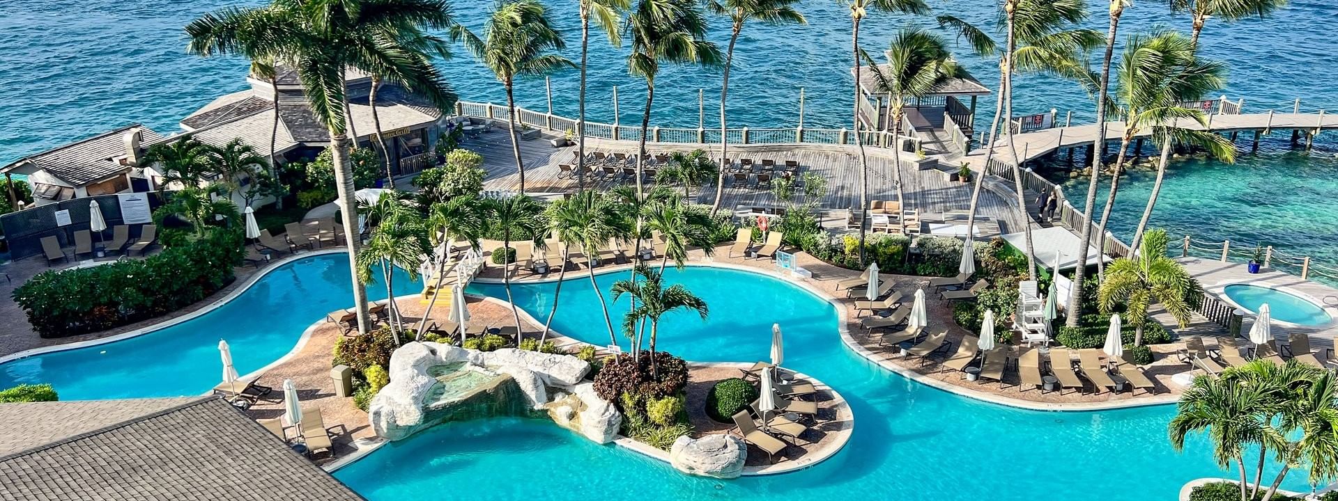 Winding pool by a harbor under a blue sky surrounding a tropical resort at Warwick Paradise Island Bahamas