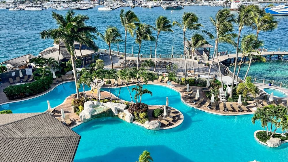 Winding pool by a harbor under a blue sky surrounding a tropical resort at Warwick Paradise Island Bahamas