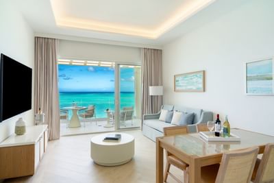 TV lounge area with dining table and ocean views in One Bedroom Beachfront Junior Suite at Windsong Resort On The Reef