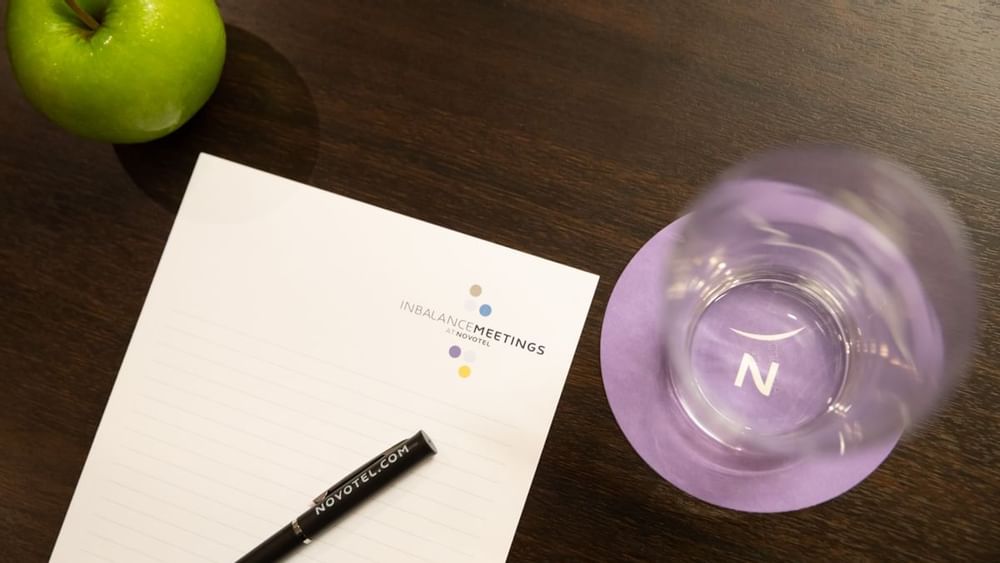 Grand Ballroom meeting table with InBalance notepad, pen, apple, and water at Novotel Sydney International Airport