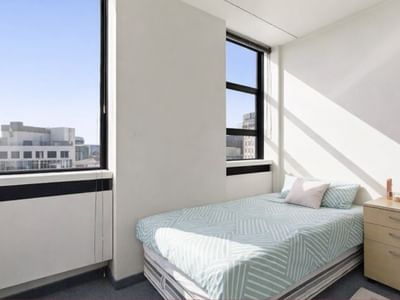 Small, tidy hotel bedroom with single bed and large windows at UniLodge Stafford House.