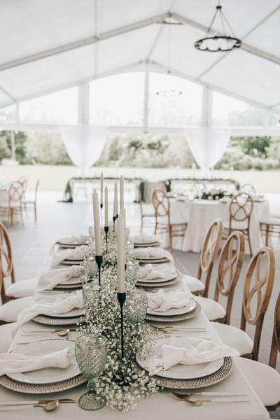 Long reception table with plates & tall candles in Spencer Meadows Pavilion at Spencer Hotel, a wedding venue London Ontario