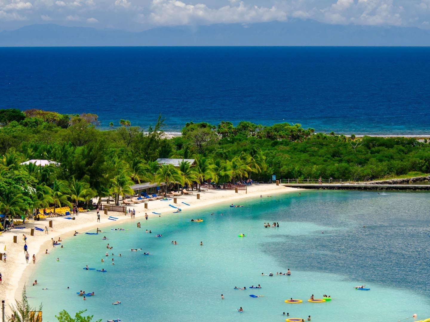 Guests swimming and relaxing on a crowded beach at Barefoot Cay Resort & Marina