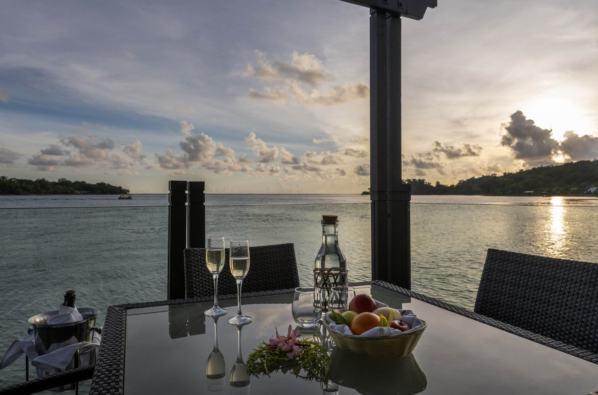 Sunset view from a patio table with champagne flutes & fresh fruit at warwick le lagon-vanuatu