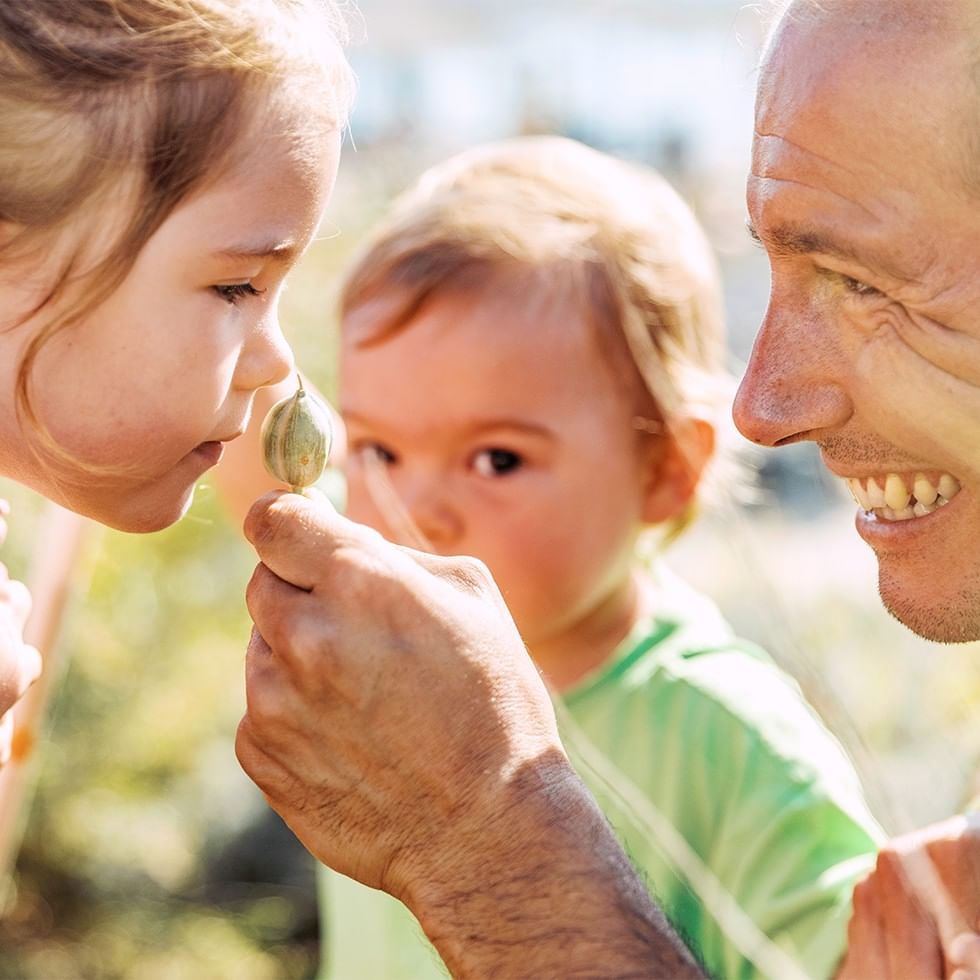 Uomo anziano che mostra un seme a due bambini piccoli.