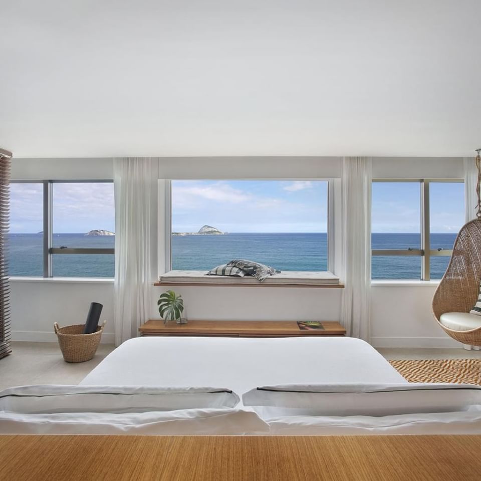 King bed and hanging egg chair arranged in Janeiro with an ocean view at Janeiro Hotel