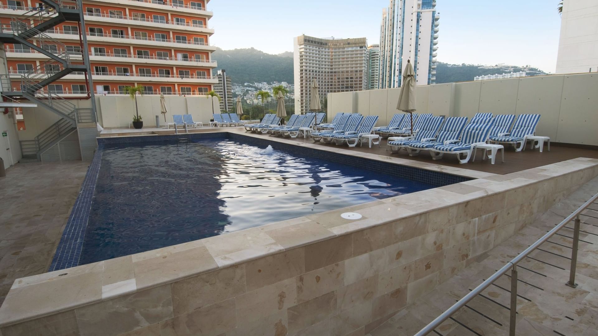 Outdoor pool area with sun beds at One Acapulco Costera