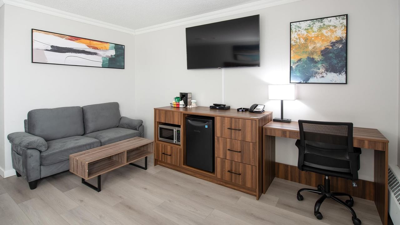 Living room area with couch, coffee table, and desk at Coast Dawson Creek Hotel.