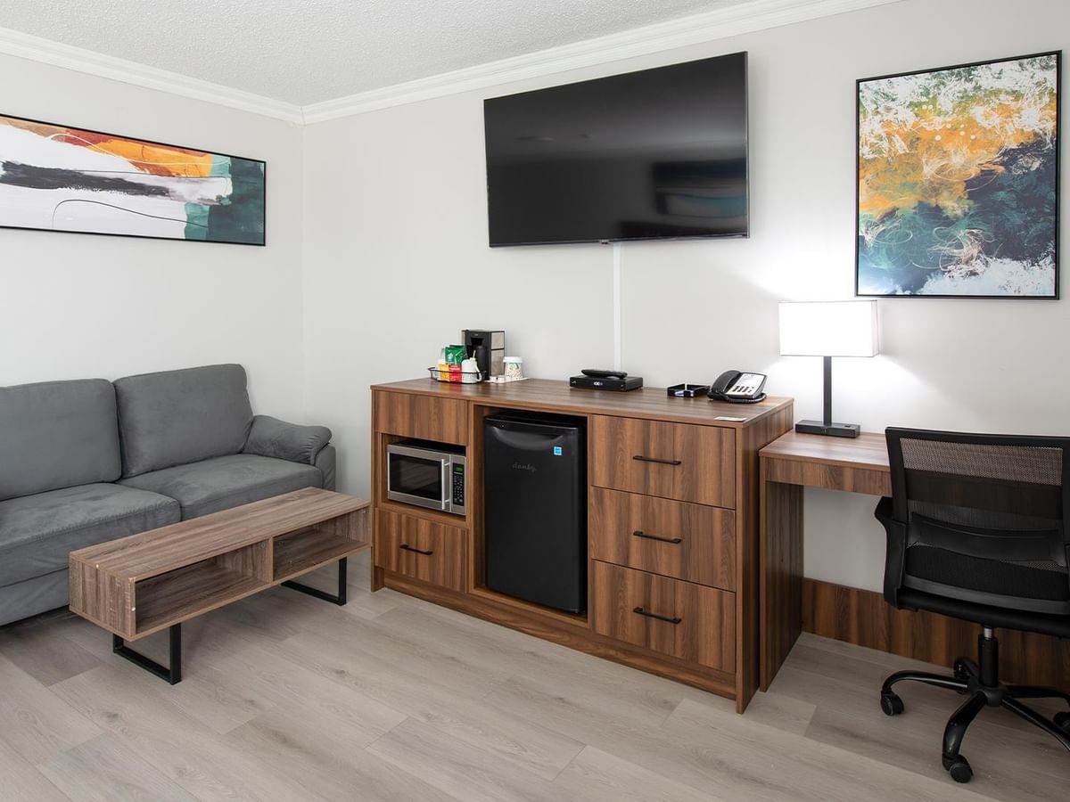 Gray couch with table, flat screen TV, desk, and chair.