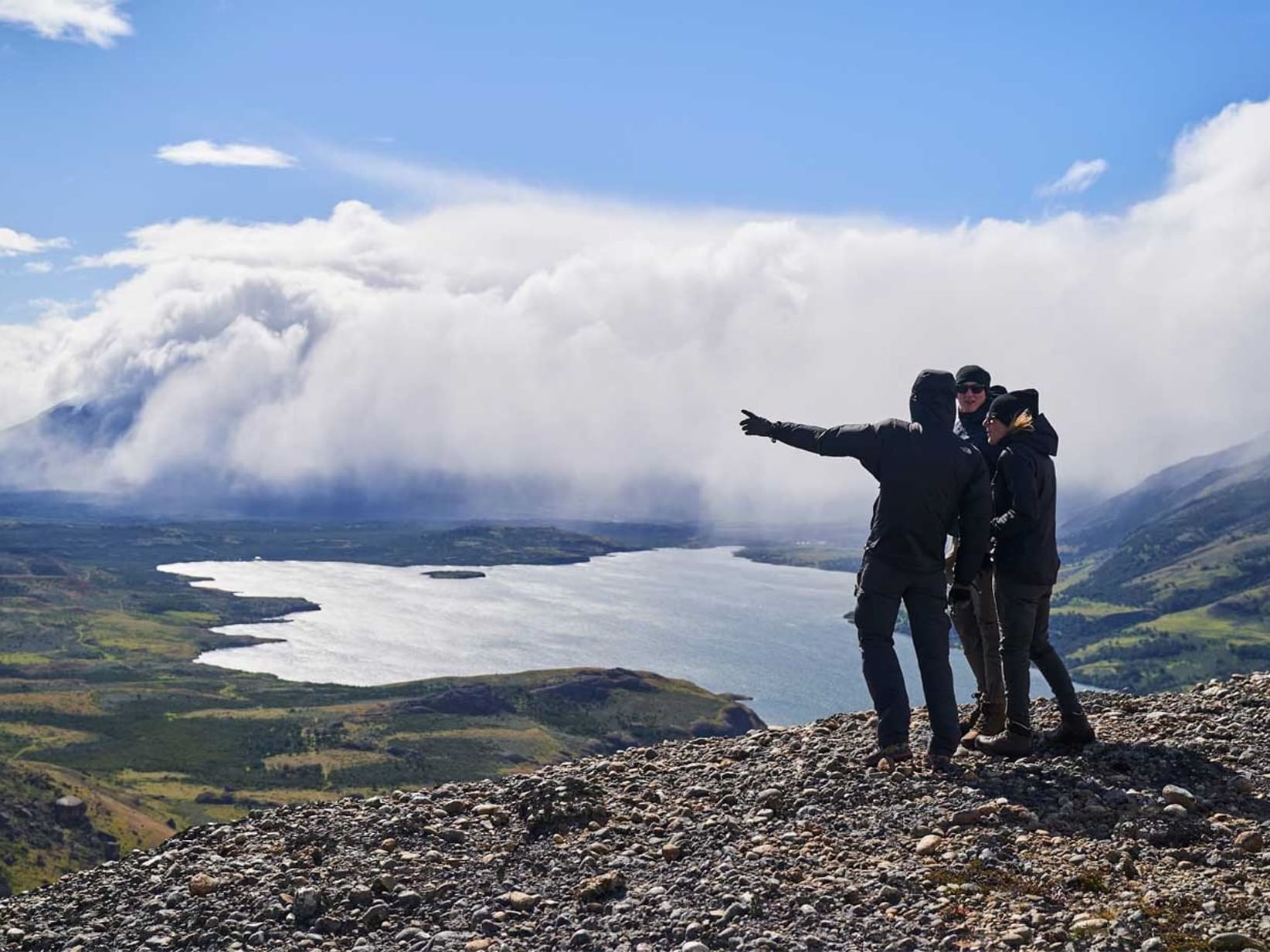 3 people talking at a mountain cliff near Singular Patagonia
