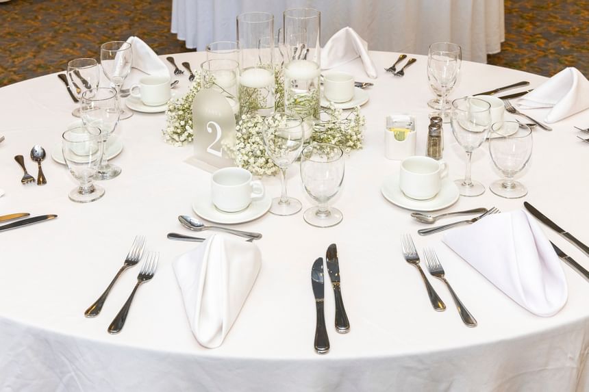 Elegantly set round banquet table with white linens & flowers, and glasses at Rodd Crowbush Golf & Beach Resort