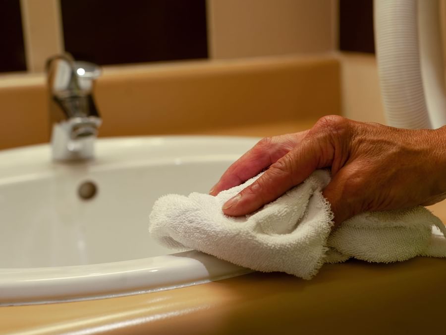 A person cleaning a face basin at Hotel Alexia