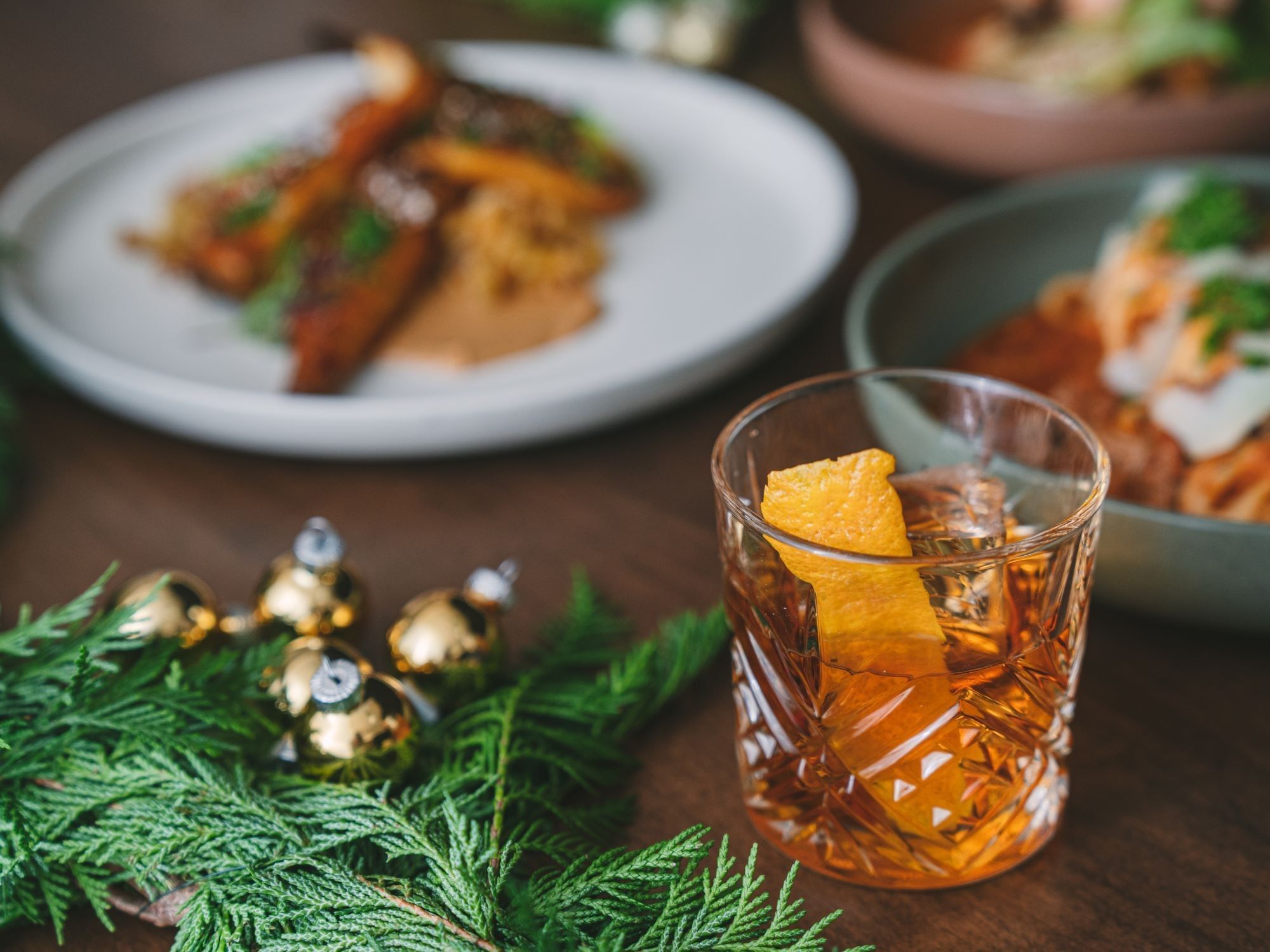 A festive table setting with a glass of whiskey and Christmas ornaments of the Pick Your Perk offer at The Delegate Hotel.