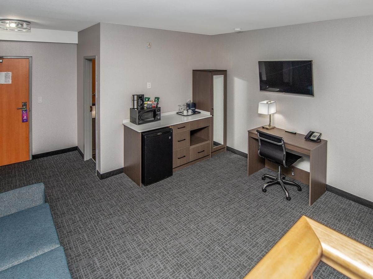 A room with a sofa bed, desk, and television.