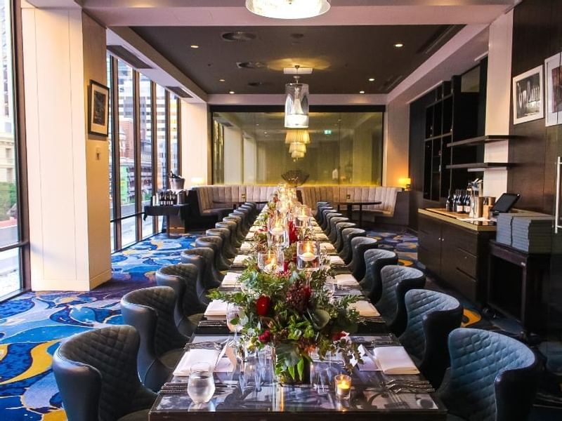 Prive Meeting room setup with a long table, floral centerpieces, and plush chairs at Sofitel Brisbane Central