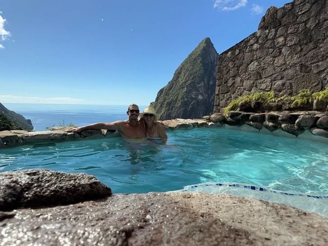 Couple enjoying a honeymoon in St. Lucia, relaxing in a private pool with a stunning view of the Pitons
