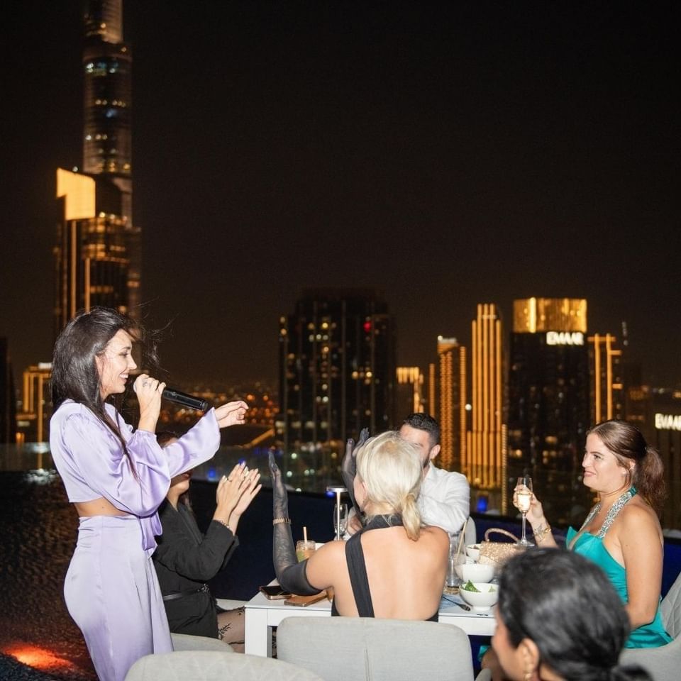 Woman singing to seated guests during the Ladies Night at Malibu Sky Lounge & Bar, one of the best rooftop lounges in Dubai
