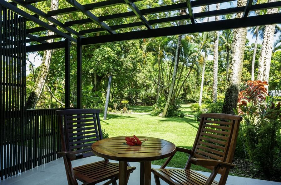 Wooden table and chairs on a tiled patio under a black pergola in Garden View Rooms at Warwick Fiji Resort and Spa