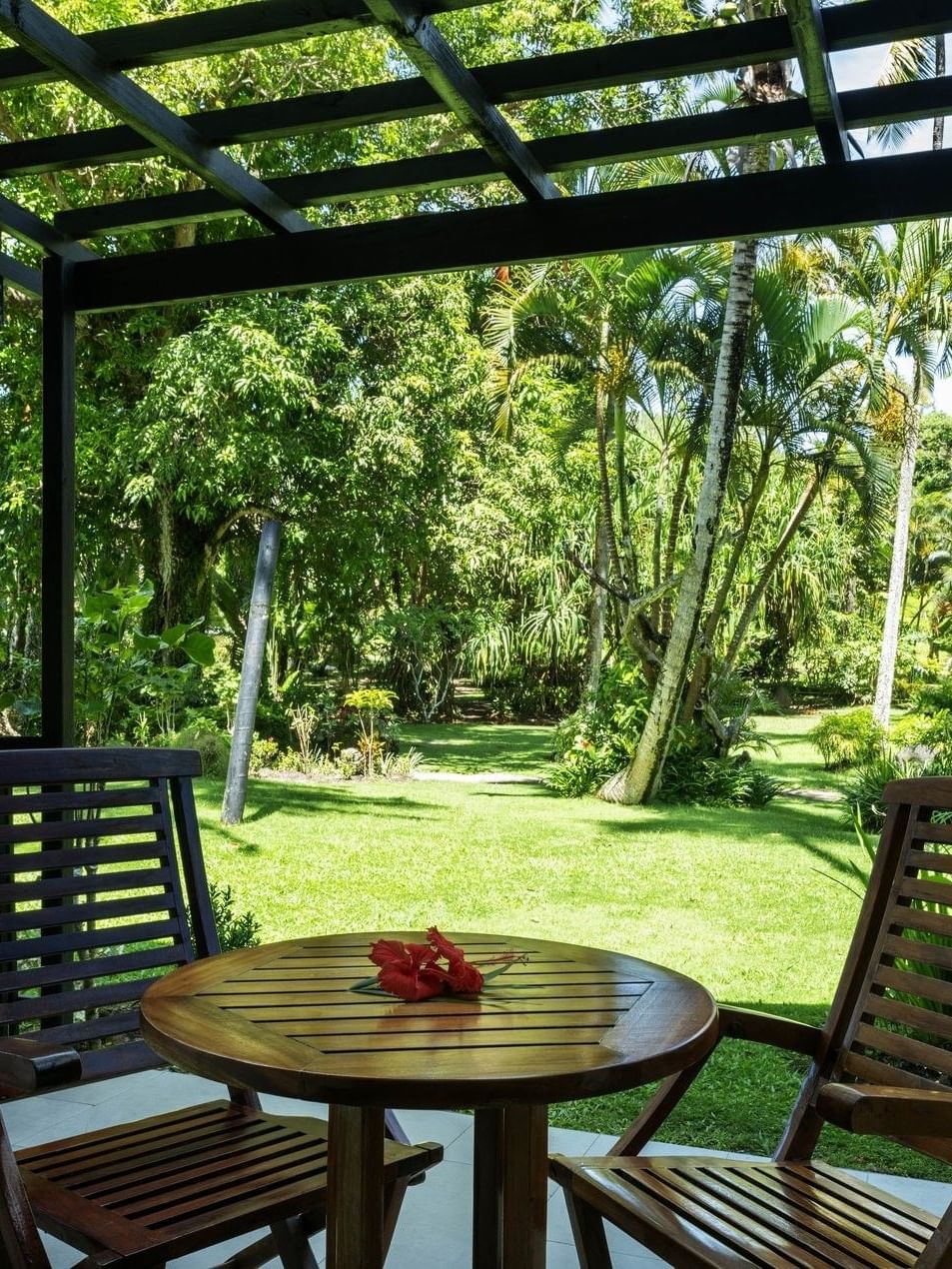 Two wooden chairs and table with garden view at Warwick Fiji Resort and Spa in Korolevu.