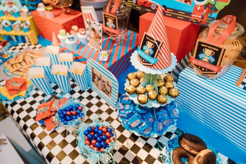 Vibrant birthday dessert table with colorful treats, popcorn boxes, chocolates, and themed decorations at Park Hyatt Saigon