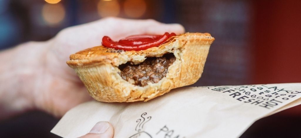 Meat pie held in hand with ketchup