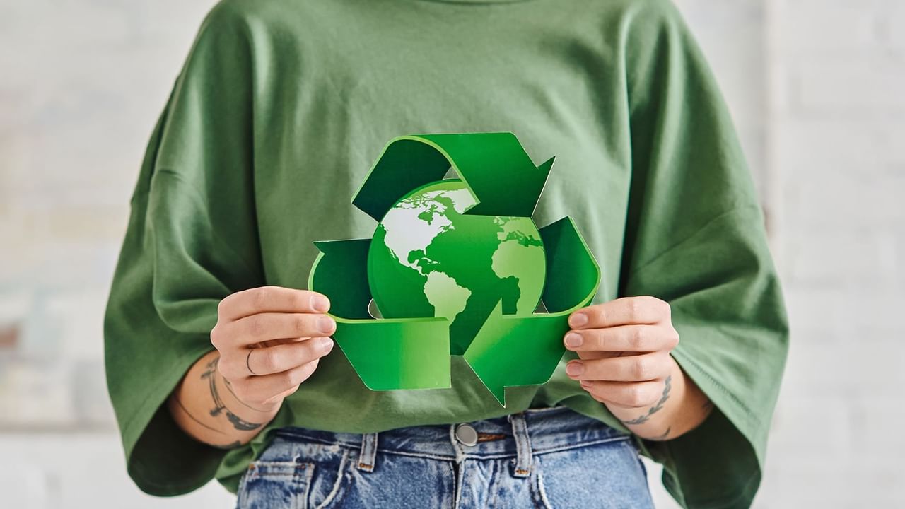 Person holding a green recycled symbol encircling a globe, emphasizing sustainability at Coast Penticton Hotel