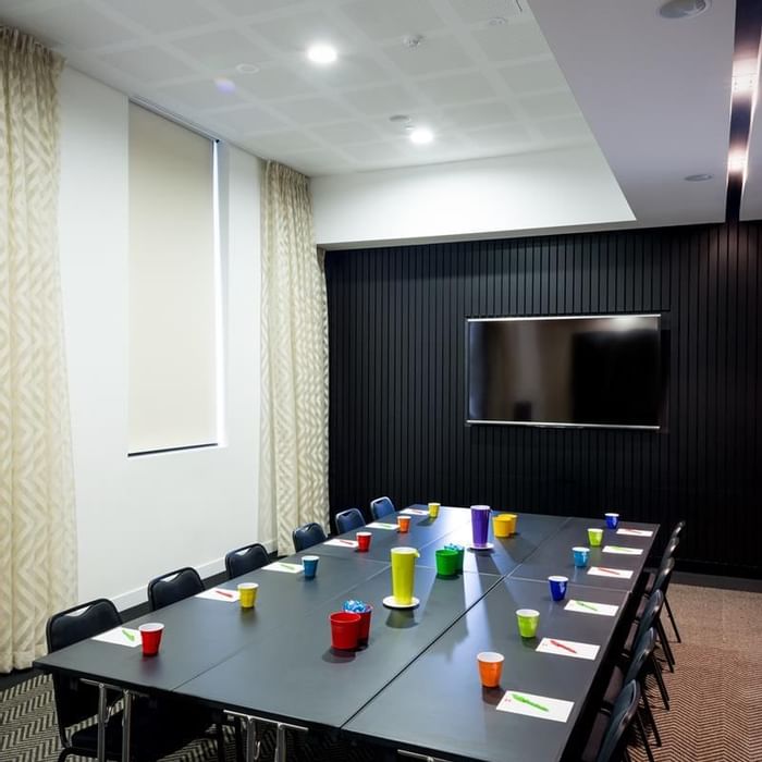 Boardroom set-up facing wall-mounted TV in The Hub at Ibis Adelaide