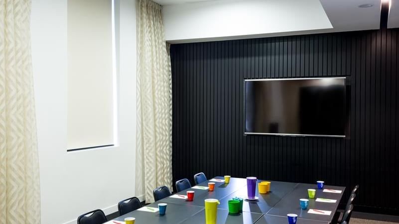 Boardroom set-up facing wall-mounted TV in The Hub at Ibis Adelaide