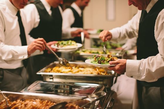 Uniformed caterers serving green salads from stainless trays on a long buffet line counter at Oregon Garden Resort