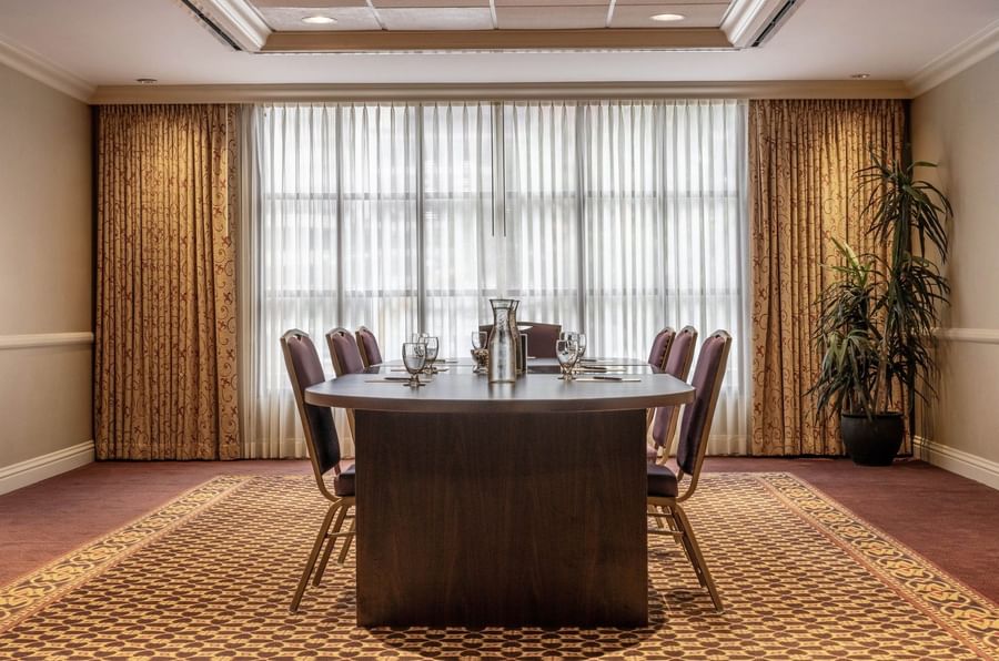 Oval wood table by purple chairs under a tray ceiling near sheer curtains in Centennial at Warwick Denver