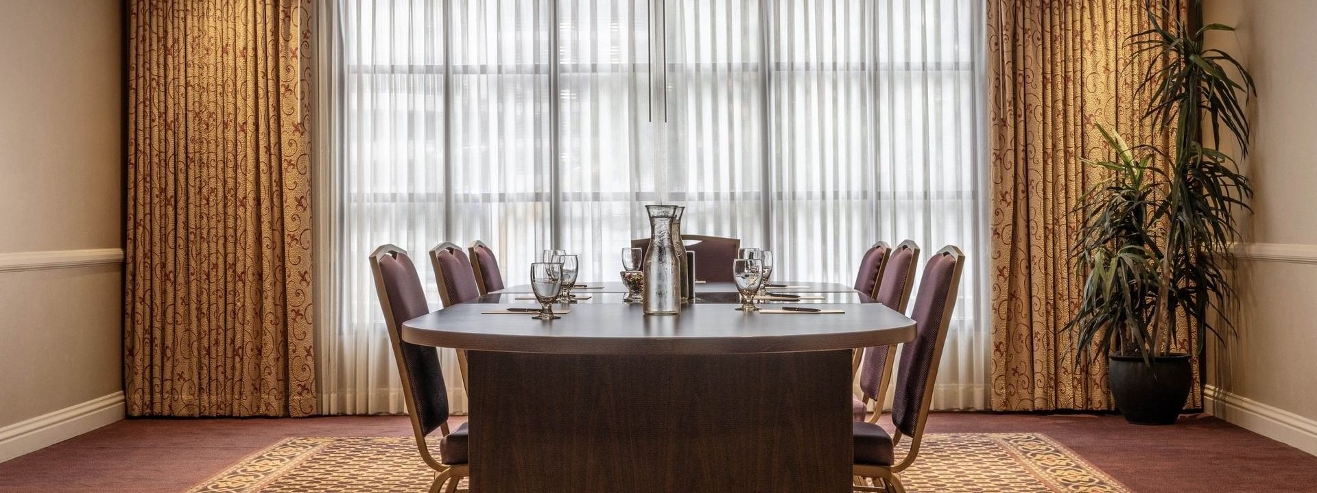 Oval wood table by purple chairs under a tray ceiling near sheer curtains in Centennial at Warwick Denver