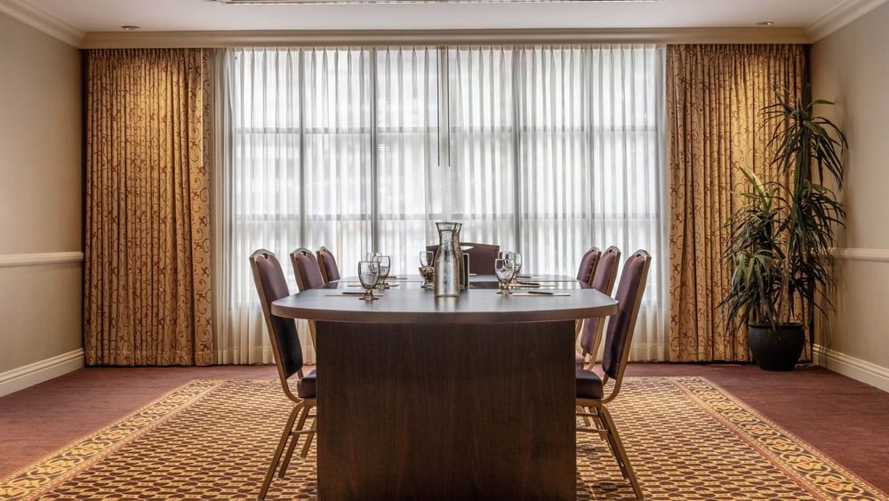 Oval wood table by purple chairs under a tray ceiling near sheer curtains in Centennial at Warwick Denver