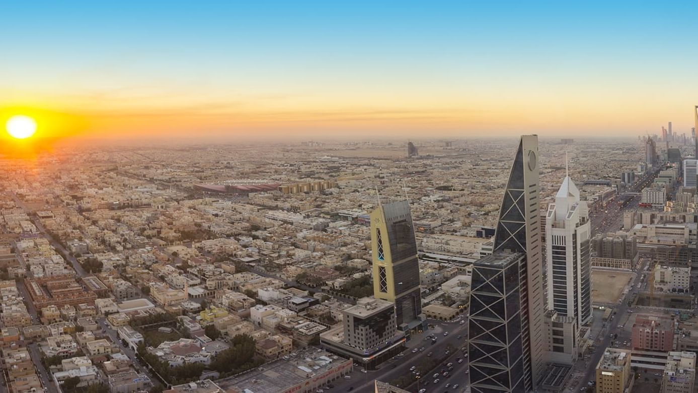Aerial view of Riyadh at sunset, showcasing modern skyscrapers and sprawling cityscape near Warwick Hotels and Resorts