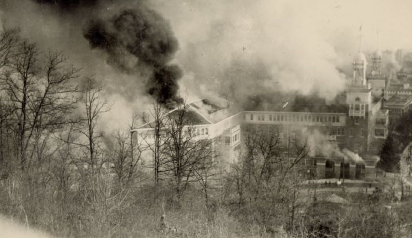 Vintage photo of Arlington Resort Hotel & Spa in smoke by a hillside under a dark cloud during a past fire